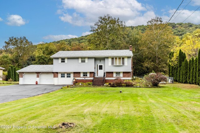 raised ranch featuring a garage and a front lawn