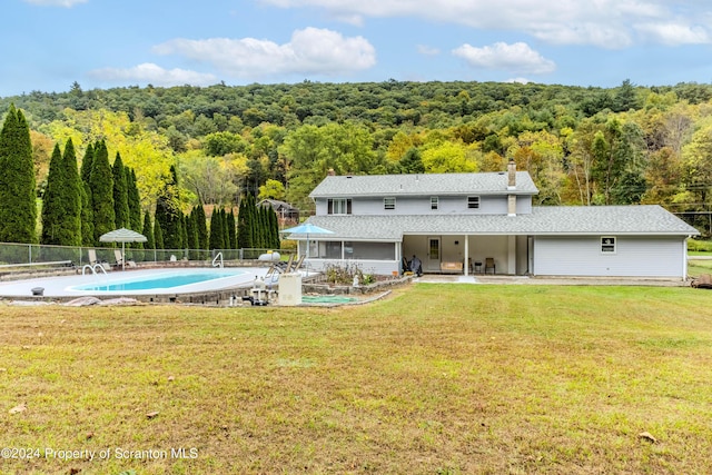 rear view of property featuring a yard, a fenced in pool, and a patio