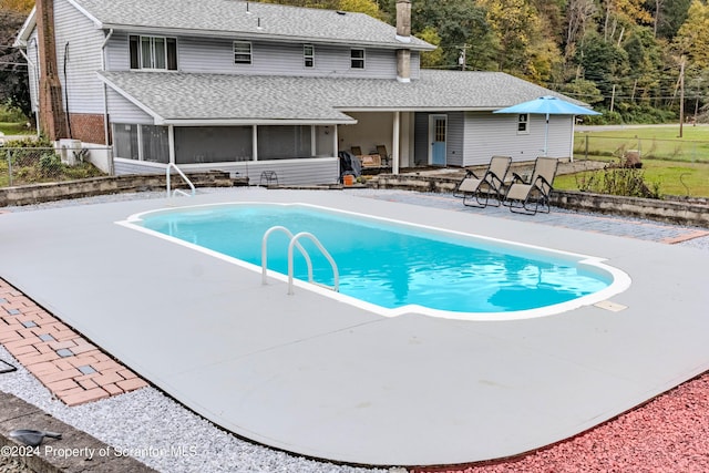 view of swimming pool with a patio area and a sunroom