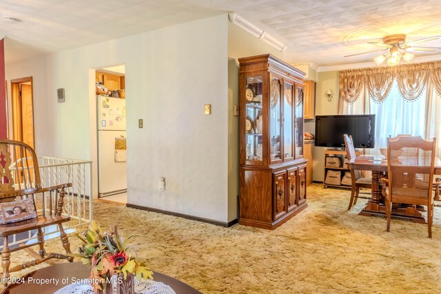 dining area featuring light carpet, ceiling fan, and ornamental molding