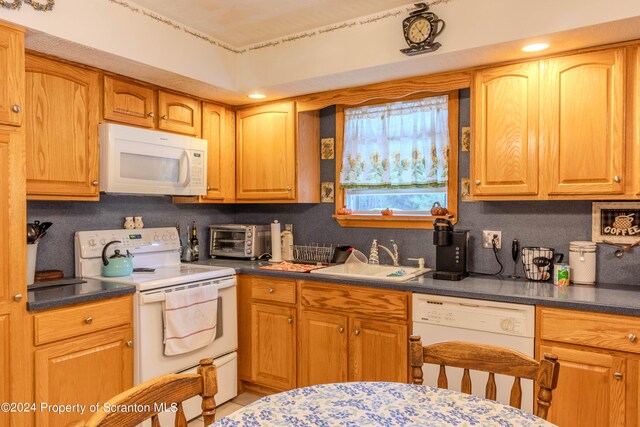 kitchen with decorative backsplash, white appliances, and sink