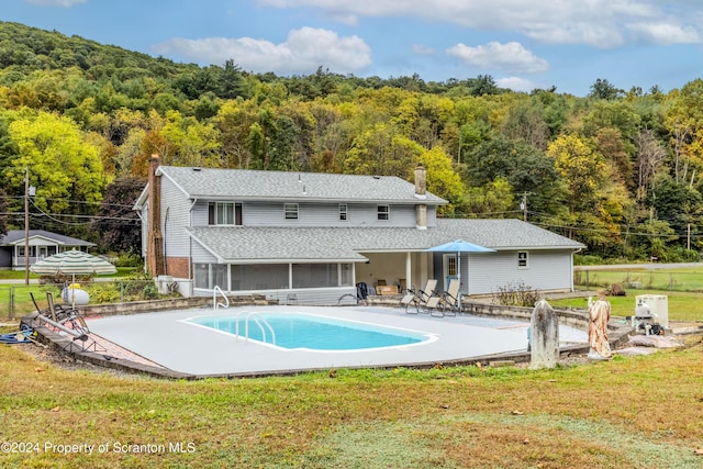 back of property with a sunroom, a patio area, and a lawn