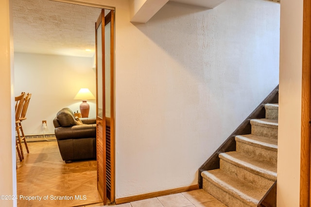 staircase featuring parquet flooring, a textured ceiling, and a baseboard heating unit