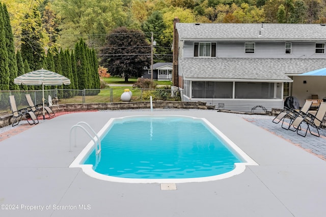 view of swimming pool with a sunroom and a patio