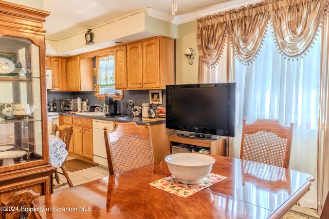 kitchen with sink, tasteful backsplash, crown molding, white dishwasher, and light tile patterned floors