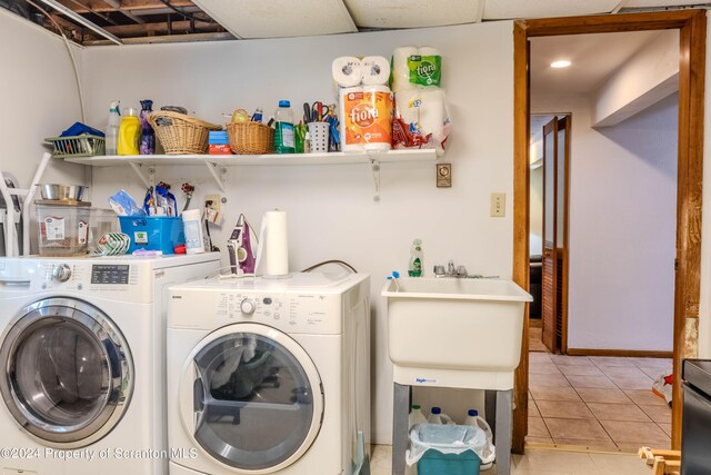 laundry room featuring washing machine and dryer, sink, and light tile patterned floors