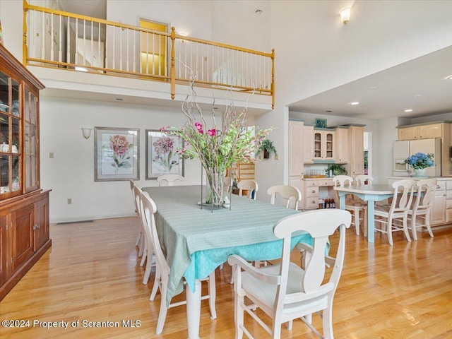 dining area featuring a high ceiling and light hardwood / wood-style flooring