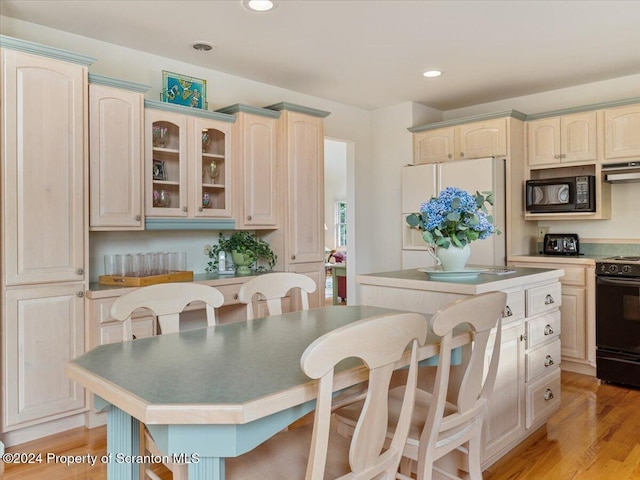 kitchen featuring a breakfast bar, ventilation hood, black appliances, light hardwood / wood-style floors, and a kitchen island