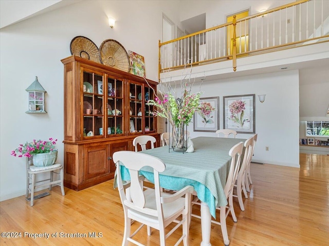 dining space with a high ceiling and light hardwood / wood-style floors