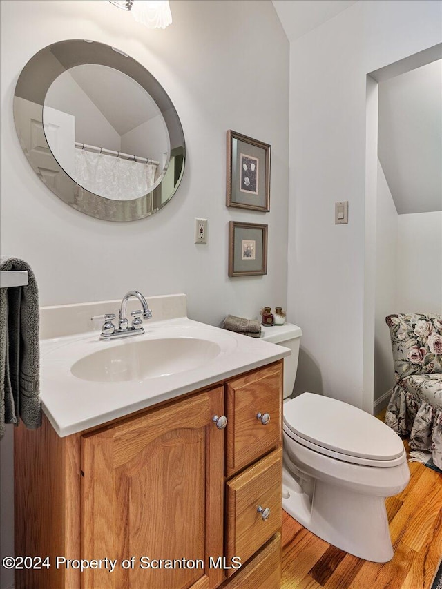 bathroom with hardwood / wood-style floors, vanity, toilet, and vaulted ceiling