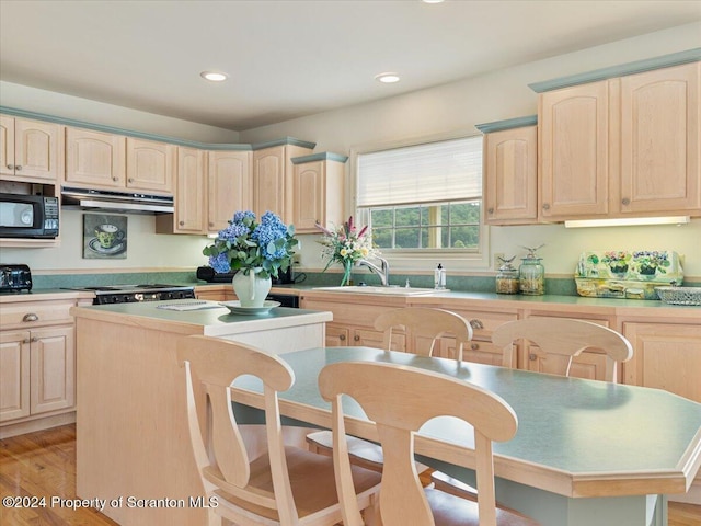 kitchen featuring sink, light hardwood / wood-style floors, light brown cabinetry, a kitchen island, and range