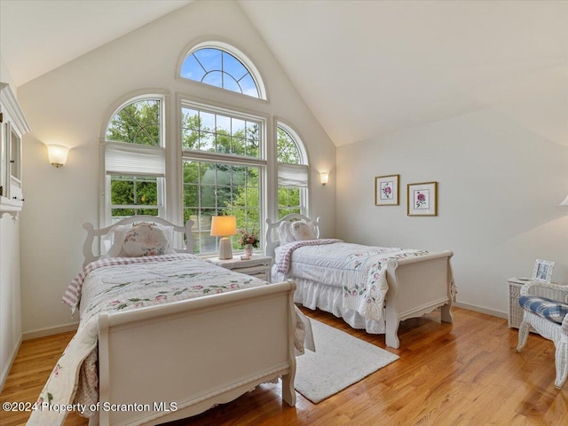 bedroom featuring light hardwood / wood-style flooring and high vaulted ceiling