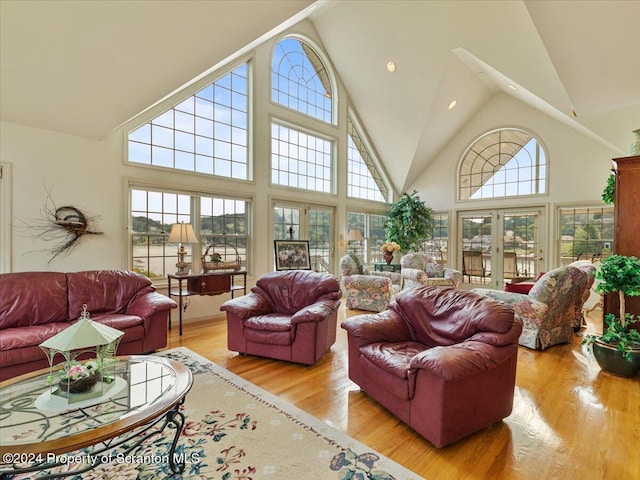 living room with light wood-type flooring, high vaulted ceiling, and french doors