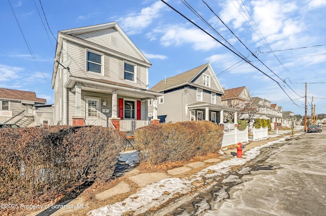 american foursquare style home with a residential view, covered porch, and fence