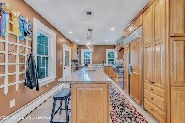 kitchen with light tile patterned flooring, a kitchen breakfast bar, light stone countertops, decorative light fixtures, and a kitchen island