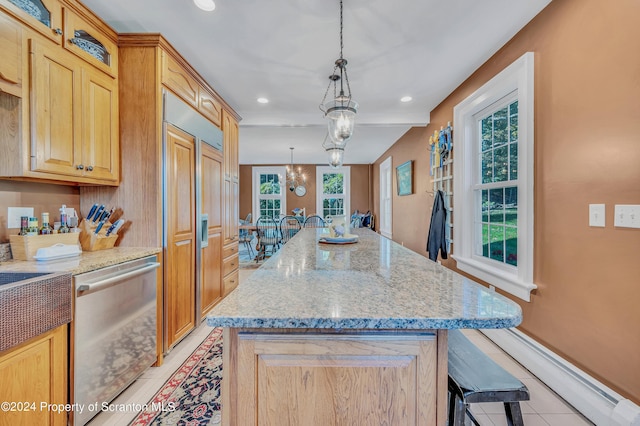 kitchen featuring a healthy amount of sunlight, a kitchen island, stainless steel dishwasher, and decorative light fixtures