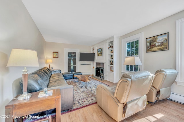 living room featuring built in shelves and light hardwood / wood-style flooring