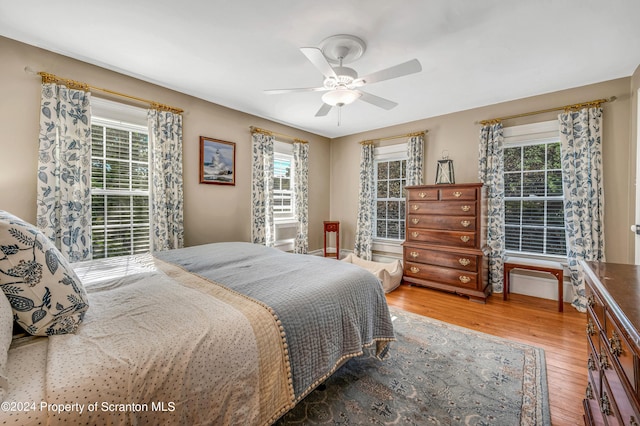 bedroom featuring multiple windows, wood-type flooring, and ceiling fan