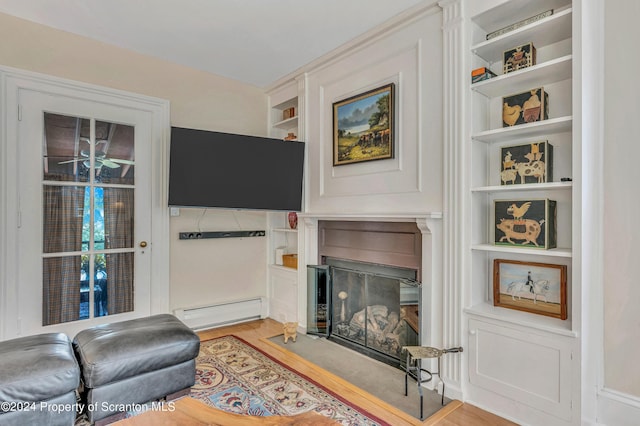 living room featuring baseboard heating, built in features, and light wood-type flooring