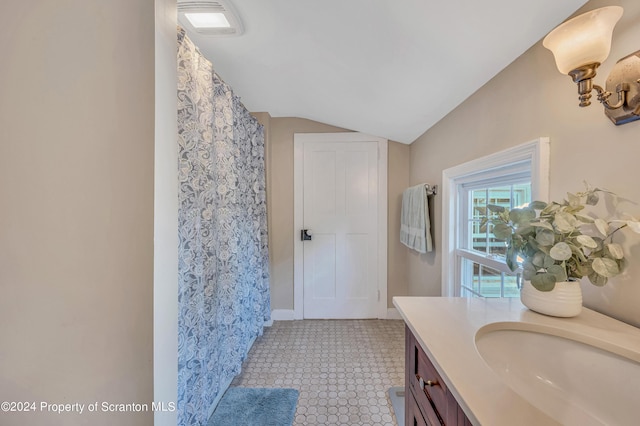 bathroom with tile patterned floors, vanity, and lofted ceiling