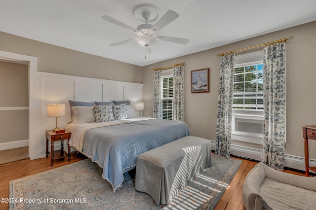 bedroom featuring ceiling fan, wood-type flooring, and multiple windows