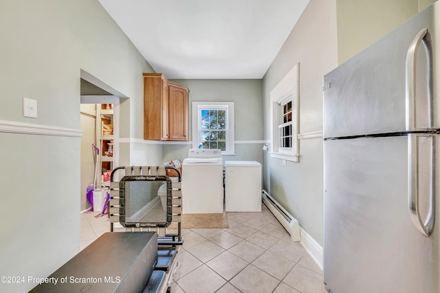 clothes washing area featuring light tile patterned flooring, washer and dryer, and a baseboard heating unit