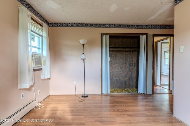 505 Yedinak Ln, Madison Twp, PA 18444 - unfurnished bedroom featuring a baseboard radiator, wood finished floors, and a textured ceiling