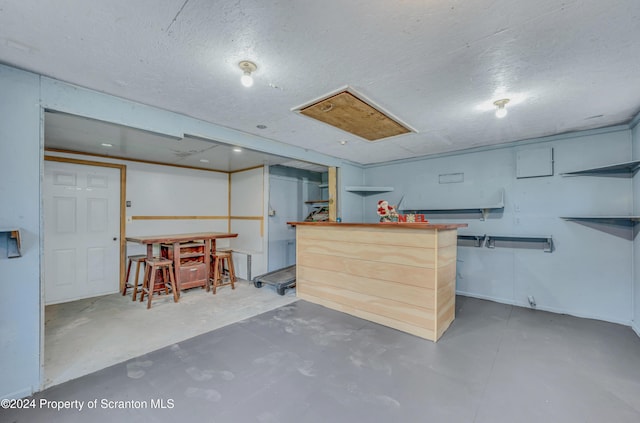 basement featuring bar area and a textured ceiling