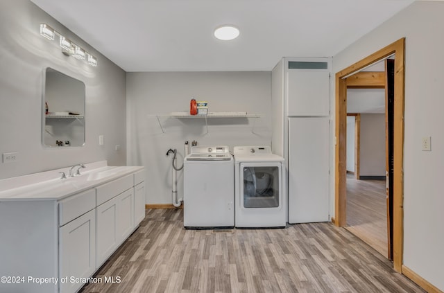 laundry room featuring cabinets, sink, washer and dryer, and light wood-type flooring