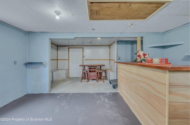 basement featuring a textured ceiling and indoor bar