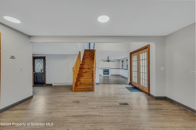 unfurnished living room with french doors, a baseboard heating unit, and hardwood / wood-style flooring