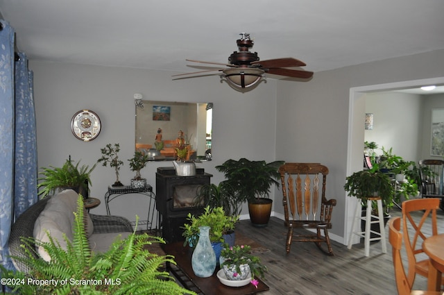 interior space with hardwood / wood-style flooring, a wood stove, and ceiling fan