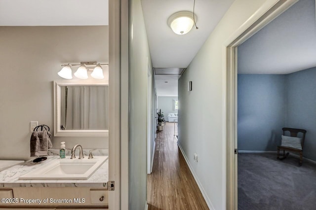 hallway featuring a sink and baseboards