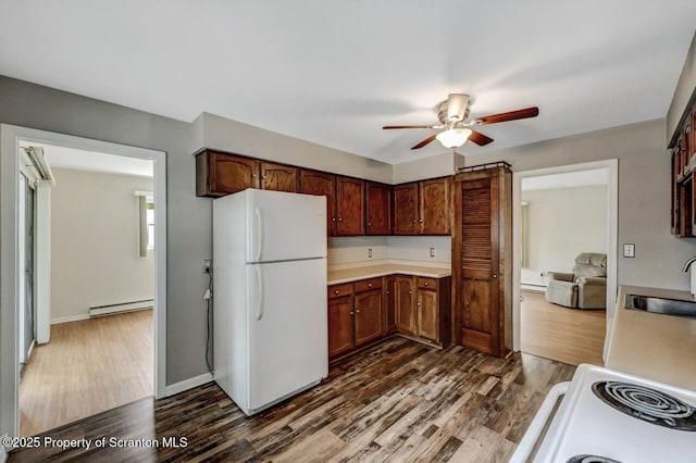 kitchen with a ceiling fan, dark wood-style flooring, light countertops, a baseboard heating unit, and white appliances