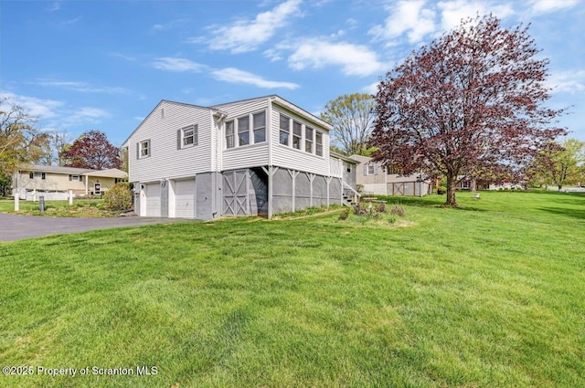view of side of home featuring a garage, a yard, and driveway