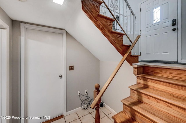 staircase with baseboards, lofted ceiling, and tile patterned floors