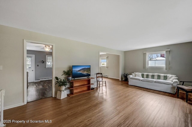 living area featuring baseboards, a baseboard heating unit, and wood finished floors