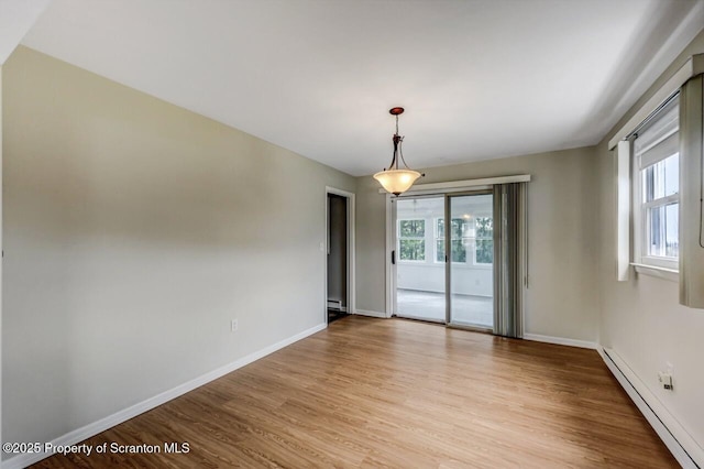empty room featuring baseboards, a baseboard heating unit, and light wood-type flooring