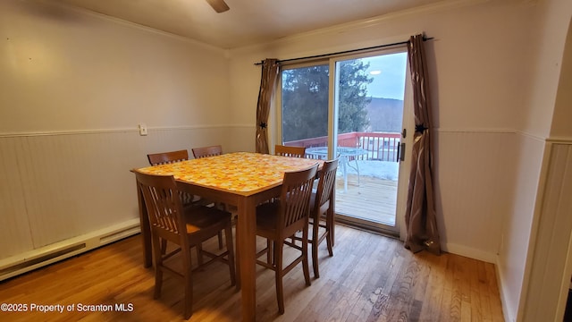 dining room with ceiling fan, ornamental molding, wood finished floors, and wainscoting