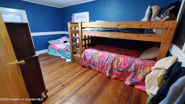 bedroom with wood-type flooring, crown molding, and baseboards