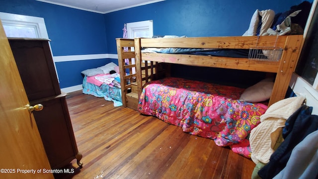bedroom with baseboards, crown molding, and hardwood / wood-style flooring
