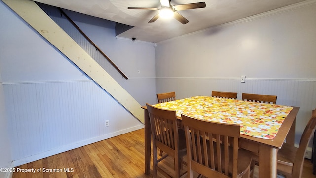 dining room featuring a wainscoted wall, a ceiling fan, hardwood / wood-style flooring, and crown molding