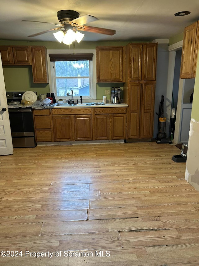 kitchen with light wood-type flooring, electric range, ceiling fan, and sink