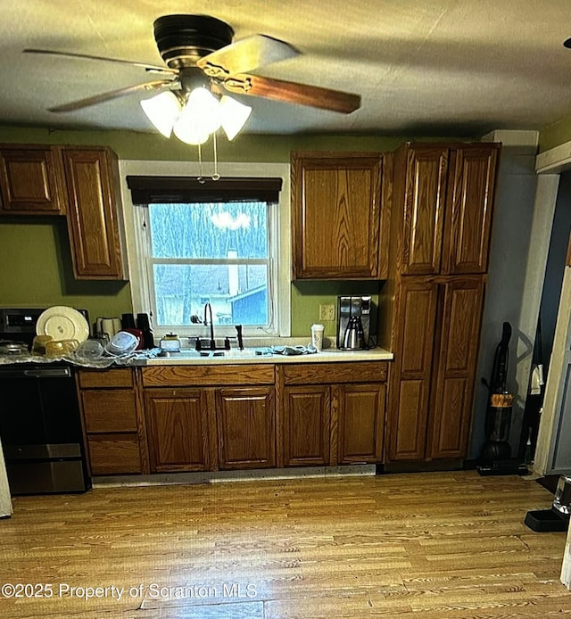 kitchen with sink, black stove, ceiling fan, and light wood-type flooring