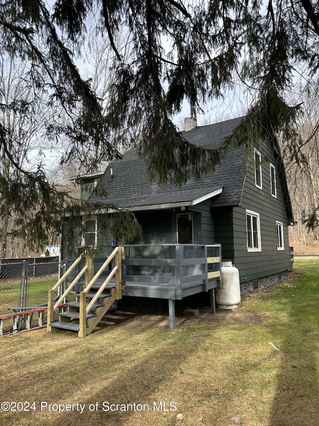 back of house with a deck and a lawn