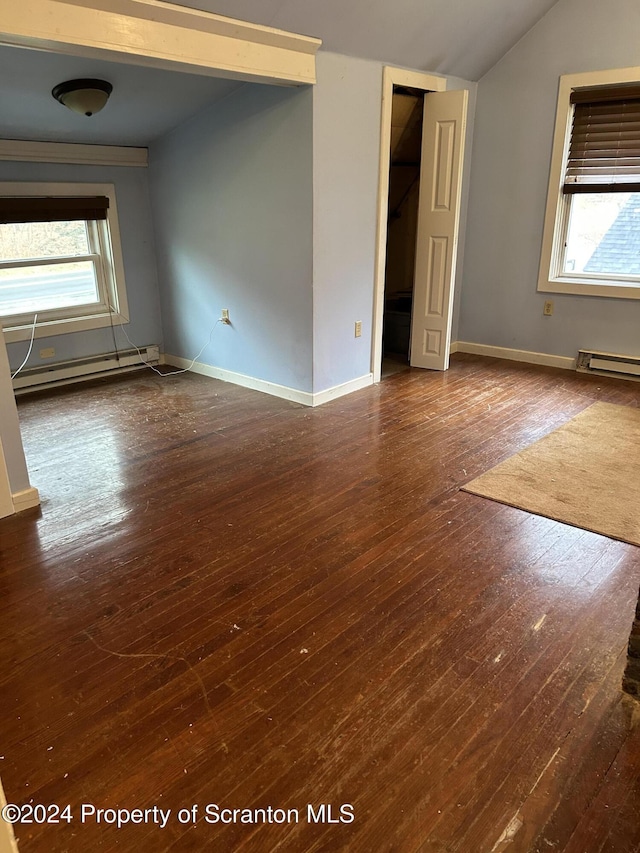 spare room with baseboard heating, a wealth of natural light, hardwood / wood-style floors, and vaulted ceiling