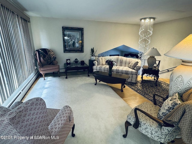 living area with a baseboard heating unit, wood finished floors, and a notable chandelier