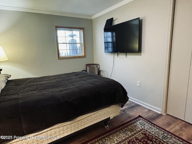 bedroom featuring baseboards, wood finished floors, and crown molding