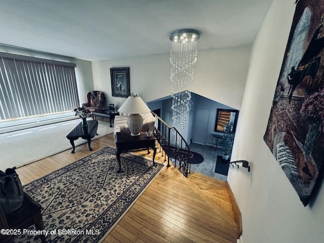 sitting room with hardwood / wood-style flooring, a chandelier, and an upstairs landing