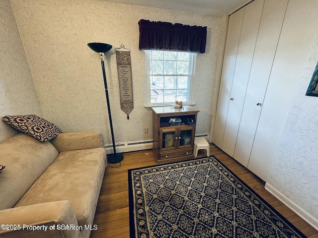 living room with a baseboard heating unit, a textured wall, and wood finished floors